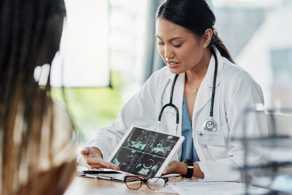 Closeup shot of a doctor showing a patient ultrasound scans on a digital tablet in her office